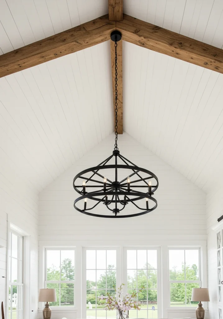 A rustic, black metal, wagon wheel chandelier hanging in a white farmhouse living room.